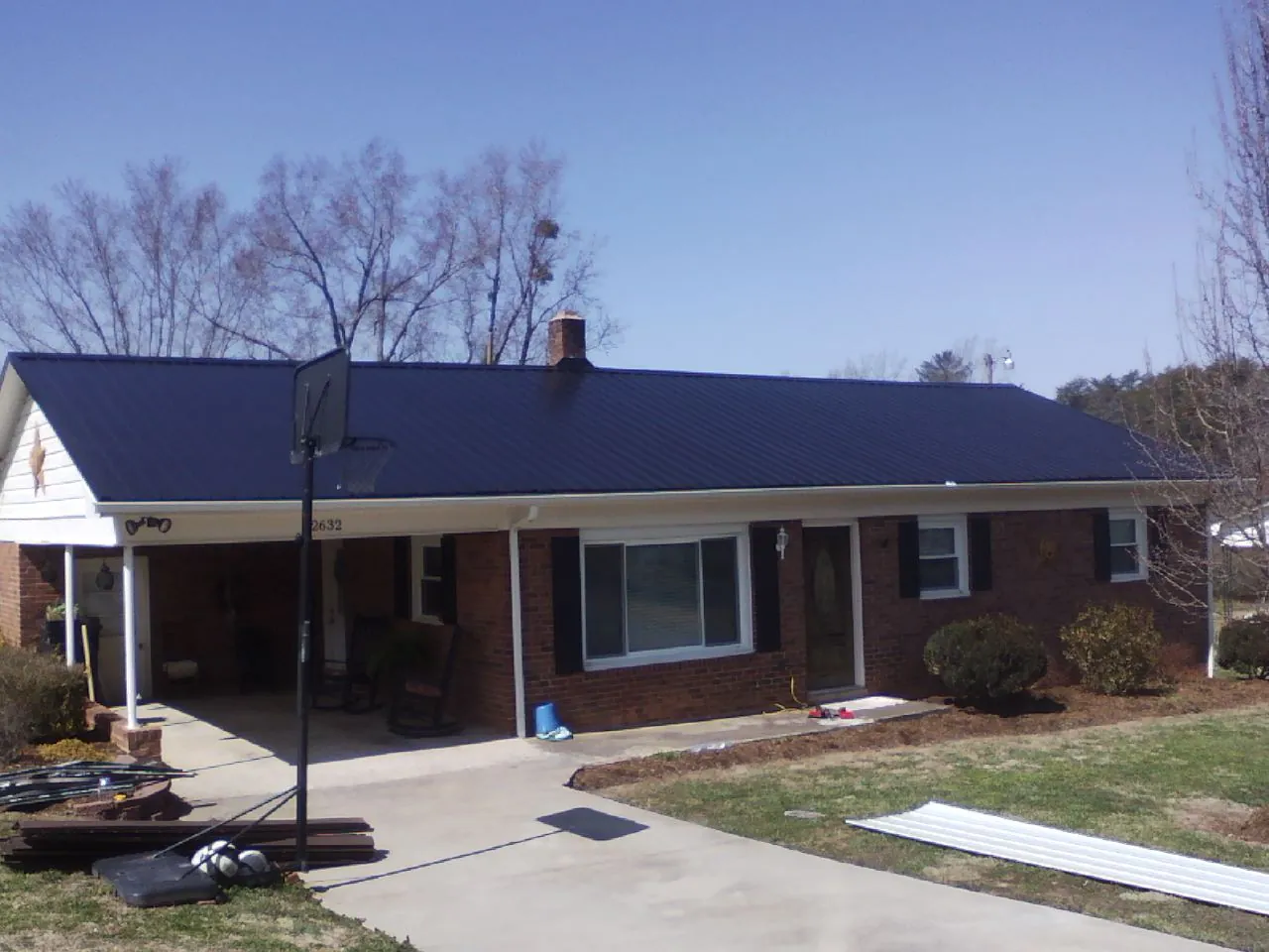 Finished dark blue metal roof on a brick ranch with a carport in Buchanan