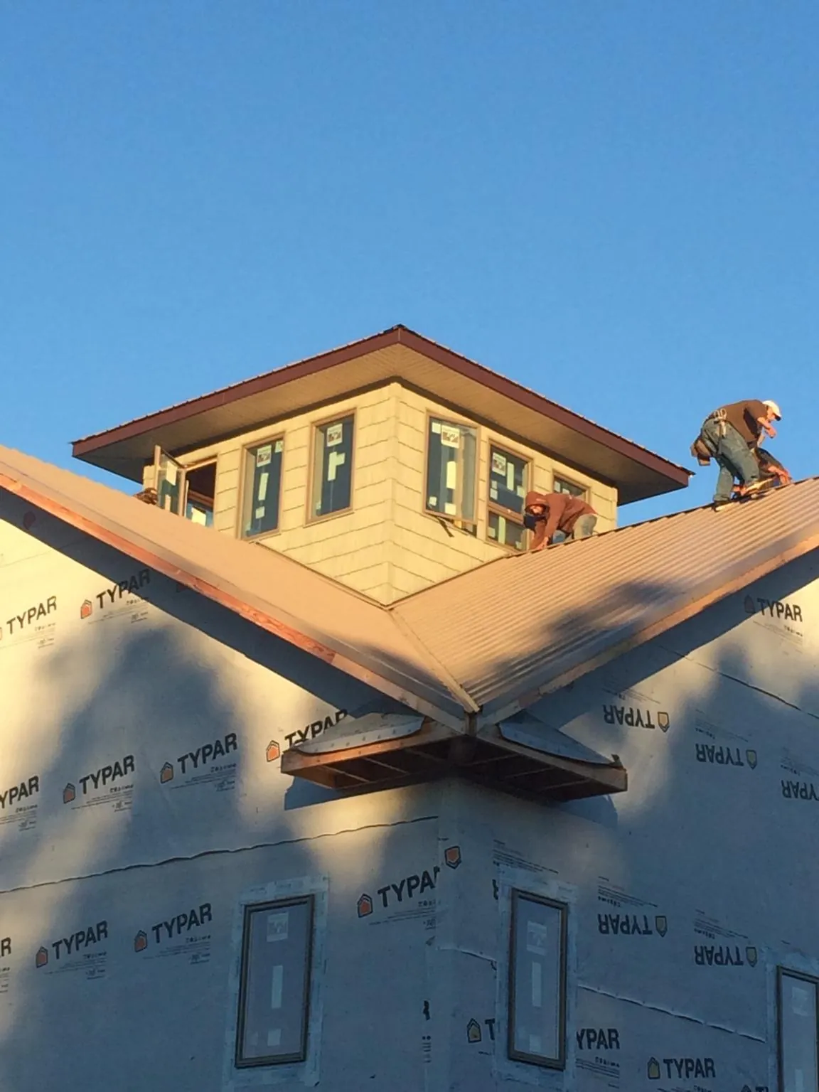 Roofers working around a rooftop cupola on a new metal roof at sunset — Roof Waterproofing in Buchanan by Roofing Brothers